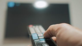 man hand holding the TV remote control and turn off smart tv. Channel surfing. Close up mans hand holding TV remote control and changing lifestyle TV channels. blurred background