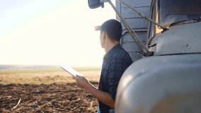smart farming. man farmer driver stands with a digital tablet near the truck. slow motion video. Portrait businessman farmer lifestyle standing in the field harvesting season car. driver farmer uses a
