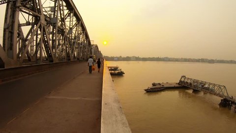 Kolkata, West Bengal / India, september 28, 2018 : Ferry boat swims up to pier under Nivedita bridge cars pedestrians on road near Ramakrishna mission sunset