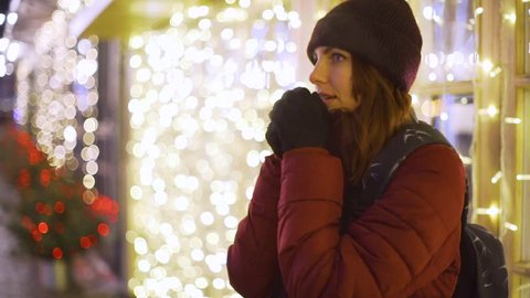 young beautiful woman walking in the night city, the streets of the city in the Christmas decorations