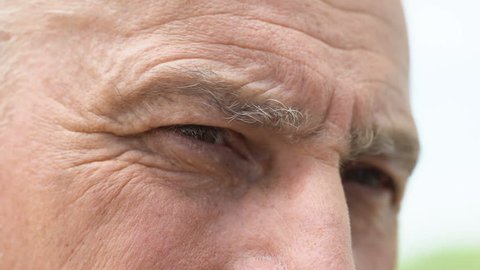 Old man with pain in soul and loneliness in eyes looking into distance, close-up