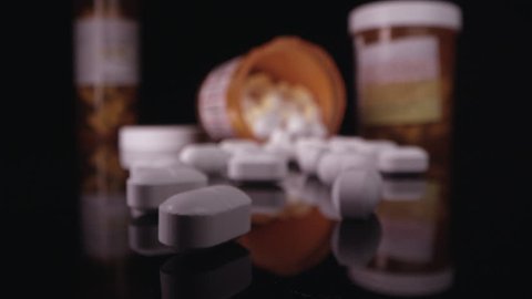 Close up view moving over prescription drugs in open bottle on table top.