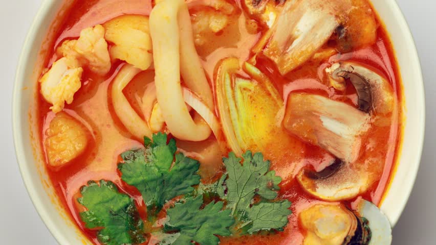 spicy Tom Yam soup spinning on table. the most popular Asian dish. The view from the top, rotates on the base