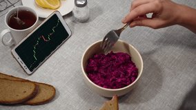 First perspective view. Businesswoman having lunch. On the table is a salad, bread, lemon and tea. She watches online currency quotes on the smartphone screen. - Powered by Shutterstock - Get 15% off with code: PIKWIZARD15