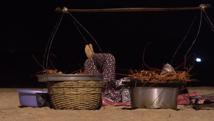 Night beach. The seller of sea delicacies, lobsters, lies on the sand and rests.