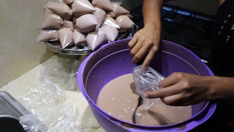 Process of pouring and tying in transparent plastic bags, delicious homemade ice cream, chocolate or cocoa based, a rich tropical fruit. Tits ice cream.
