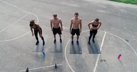 aerial, drone footage of group of well-trained men and women doing exercises, outdoor in the morning
