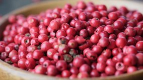 Close up footage of red peppercorns in wooden bowl. Selective focus.