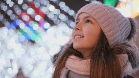 A girl looks up at a Christmas tree while standing in the square. Close-up video