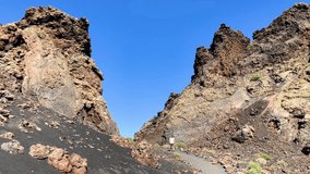 A man walking to tourist trek trail of the Crater Caldera de Los Cuervos, Timanfaya National Park, Lanzarote, Canary Islands, 4k footage video.