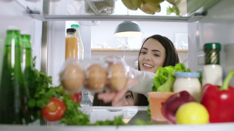 Young woman takes a carton of eggs from the refrigerator. POV from inside the refrigerator.