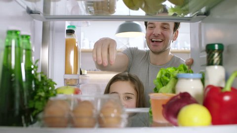 Dad and daughter take eggs from the refrigerator. POV from inside the refrigerator.
