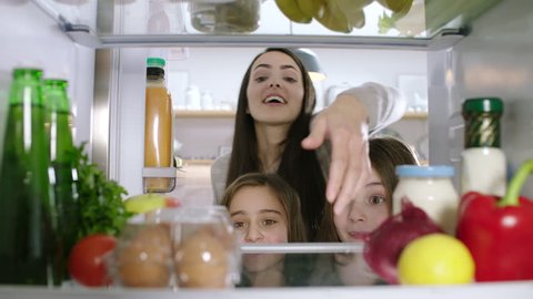 Mother and her daughters take eggs from the refrigerator. POV from inside the refrigerator.