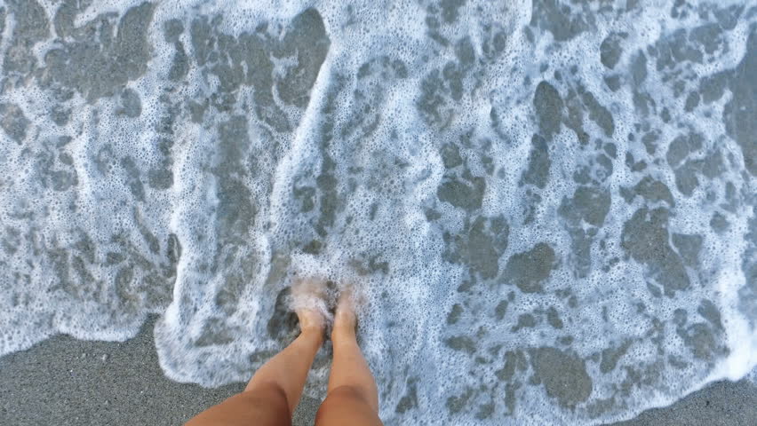 Woman standing in the shallow sea enjoying and refreshing on the small waves in the morning