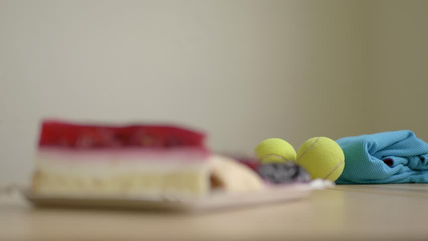 Making choice of sport or sweets, focus changes from tennis balls to cakes. Temptation and doubts between training and eating. Hard choices of unhealthy food and health. Royalty-Free Stock Footage #1021389364
