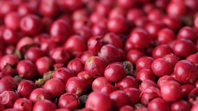 Close up footage of red peppercorns on wooden table. Selective focus.