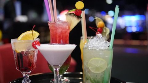 Colorful alcohol drinks and cocktails in various glasses on bokeh background in nightclub, bar, disco or pub - mojito, margarita, pina colada, sazerac, manhattan prepared by bartender.