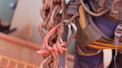 4 K Footage of 10.5 MM dynamic rope low elastic elongation fasten with barrel knot connecting into carabiner and clipping hanging on rope access industrial safety chair harness loop equipment 