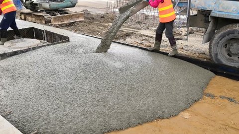 pouring concrete from a concrete mixer.
Man working with concrete mixer.Pouring concrete mix on concreting formwork.