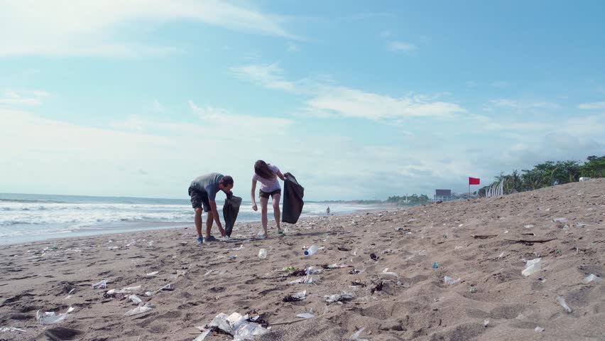 Young volunteers boy and girl with garbage bags cleaning area in dirty beach of the ocean, People and ecology. Volunteer concept. Royalty-Free Stock Footage #1021414435
