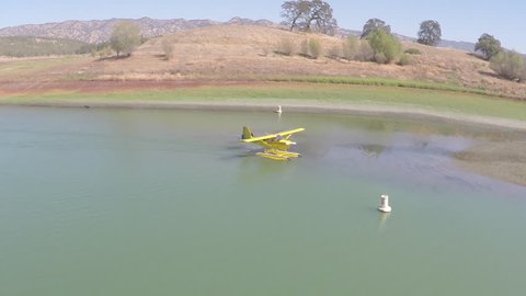 A small floatplane taxiing to shore after landing in a small lake inlet.