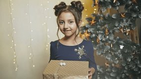 A point of view perspective of an excited young girl giving a present while standing beside a Christmas tree - slow motion.