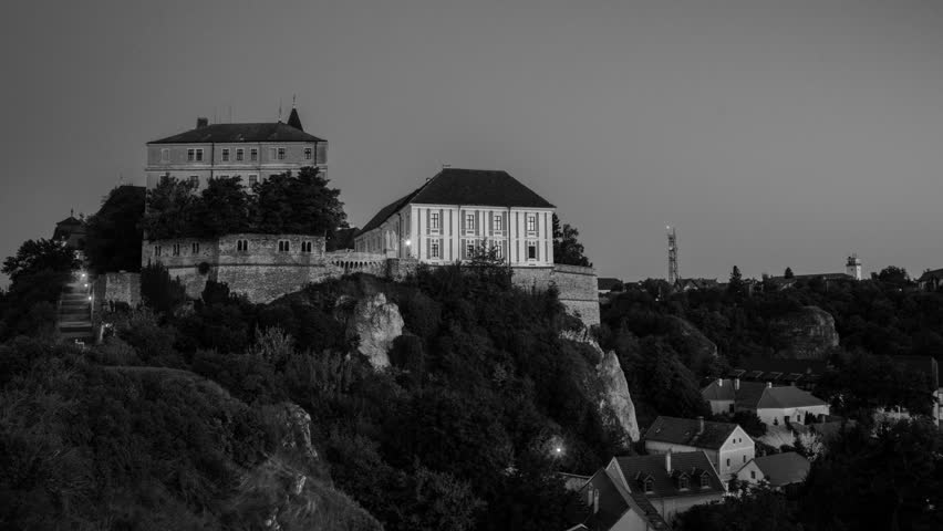 Veszprem, Hungary. View of illuminated landmarks of Castle hill at night. Time-lapse at sunset with sky. Black and white