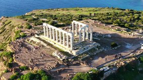 Aerial drone bird's eye view video of archaeological site of Cape Sounio and magnificent deep blue bay with iconic Ancient temple of Poseidon, Attica, Greece