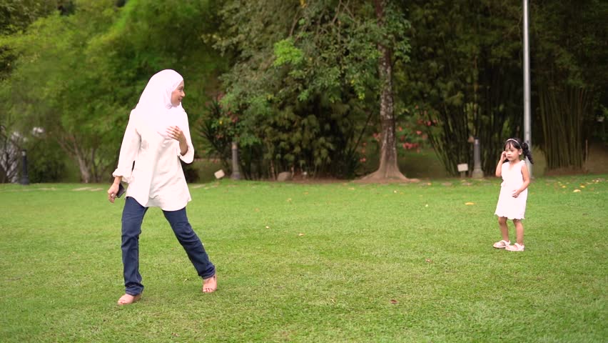 Cute little girl running and chasing her mother in slow motion at park.