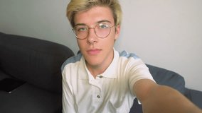 Handsome teenage boy with piercing recording video for his blog. Smiling teenager in eyeglasses recording video message. Concept of blogging.