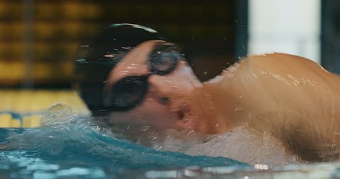 Professional swimmer with googles jumping and diving in a freestyle pool. Shot with RED Camera in 8K. Concept of sport, swimming pool, competition, fitness.