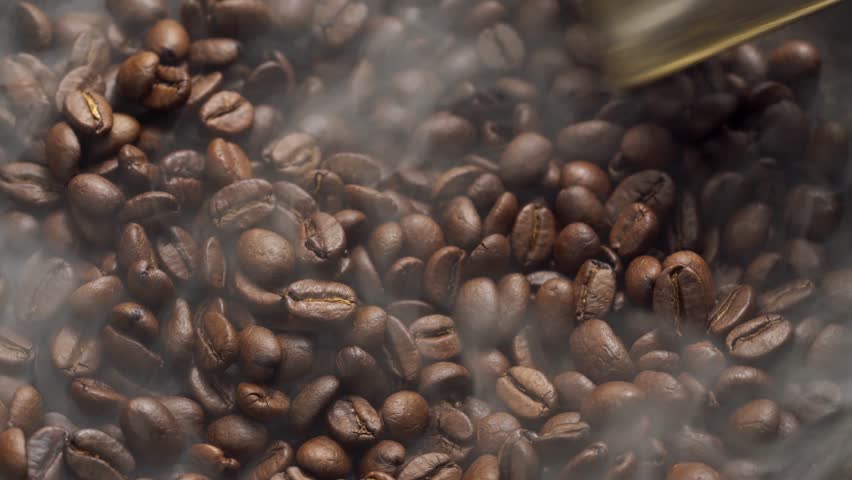 Fragrant coffee beans are roasted in a frying pan, smoke comes from coffee beans. The whole composition scrolls slowly around the camera. Scoop stir coffee beans. | Shutterstock HD Video #1021452235