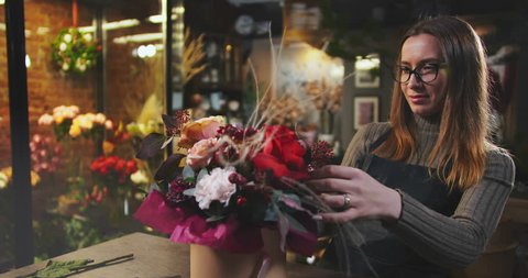 Caucasian woman completing beautiful bouquet in flower shop. Flower sale and delivery. Small business concept