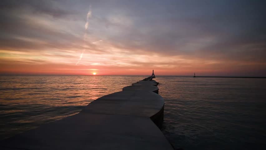 Sunrise featuring the Port Washington Wisconsin lighthouse, breakwater and birds. Absolutely beautiful sky, could be sunset, could be sunrise.