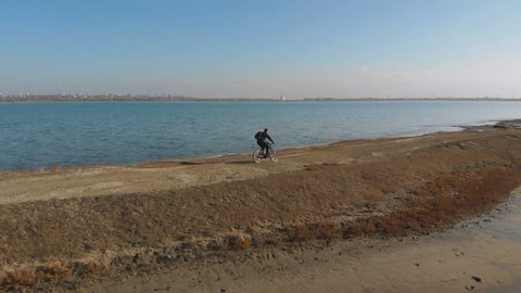 Man riding mountain bike near the lake in autumn nature. Shooting from drone