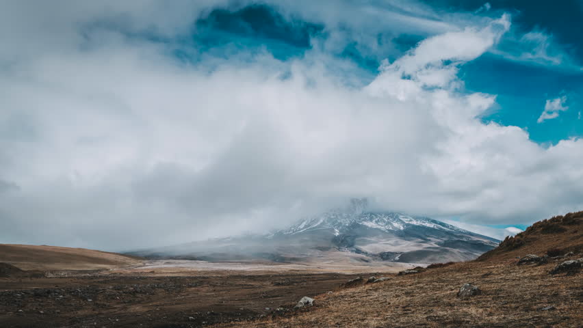 Picturesque mountain landscape of Cotopaxi, Ecuador, with steep mountain peak covered in snow under dense moving clouds