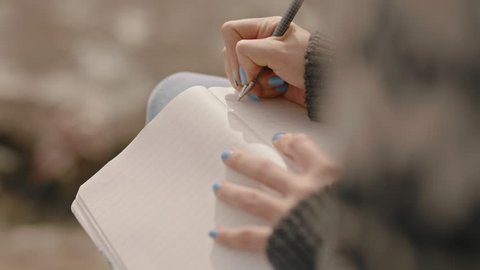 close up hands woman writing in diary journal teenage girl expressing lonely thoughts on seaside beach