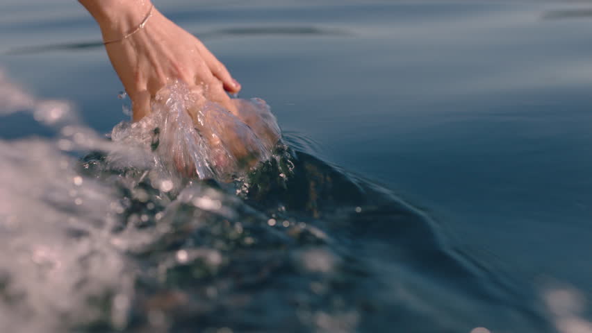 close up woman hand touching water waves splashing tourist enjoying boat ride