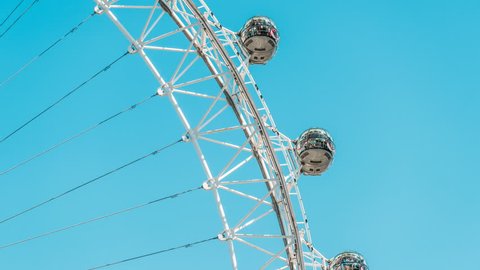 Timelapse, time lapse of closeup view on London Eye on summer day, blue clear sky, people riding in capsules on Cantilevered observation wheel in UK