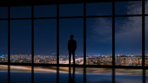 The man standing near window on a night city background. time lapse