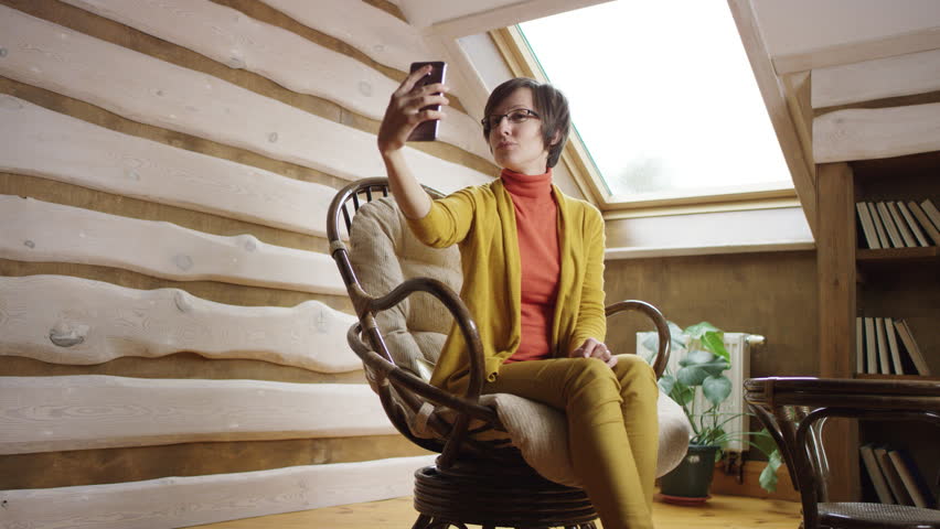 Adult pretty woman in glasses takes selfshot on attic