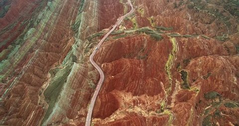 aerial view of one tourist bus driving on rod in colorful Danxia landform of Zhangye Danxia National Geological Park of China