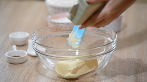 Baking ingredients in the kitchen with a bowl of flour, eggs, sugar, jug of milk and butter ready to bake a cake or make batter.