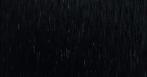 4k Heavy wall of rain falling in front of the camera against black screen. Raindrops splashing. Rain closeup vfx insert. Practical seamlessly loopable footage. Heavy rainstorm hitting black surface.

