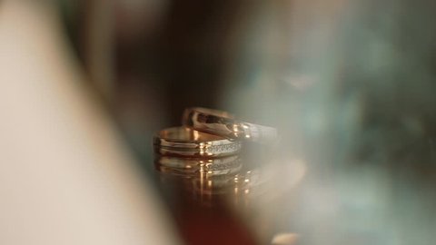 Two gold wedding rings lying on a table whit decorations shining with light close up macro. Transfusion of light on rings.. Close up