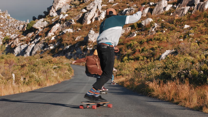 Young multi ethnic friends longboarding together riding skateboard cruising downhill on countryside road having fun enjoying relaxed summer vacation | Shutterstock HD Video #1021486621