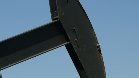 Close up of working oil pump with blue sky in the background