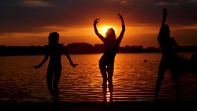 Video clip of three girls in bikinis dancing against the backdrop of the sunset on the beach