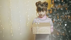 Adorable, shy young girl giving Christmas present