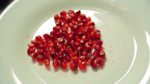Heart of pomegranate seeds on a white plate. Close-up.